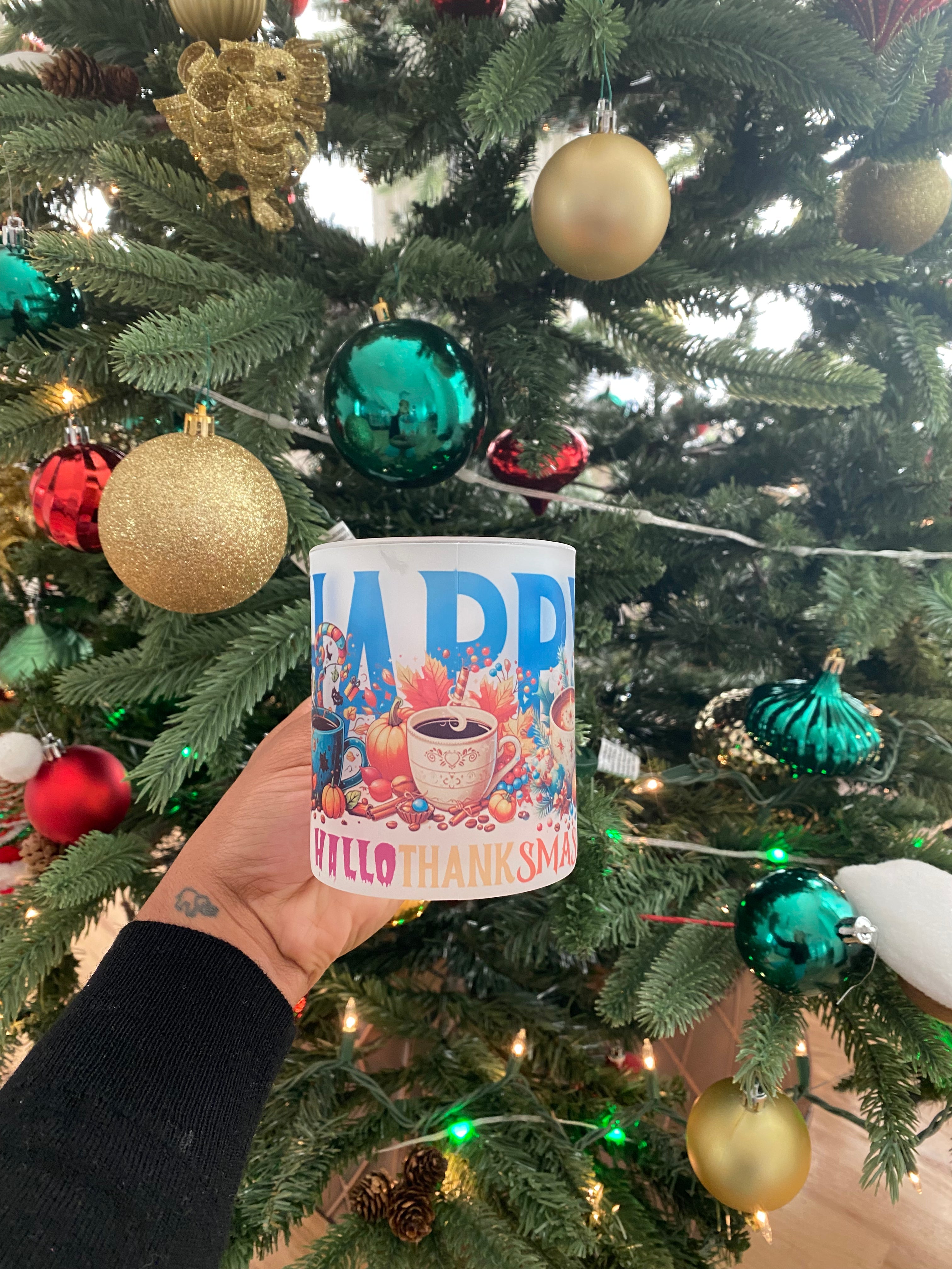 Person holding a mug with colorful design in front of a decorated Christmas tree